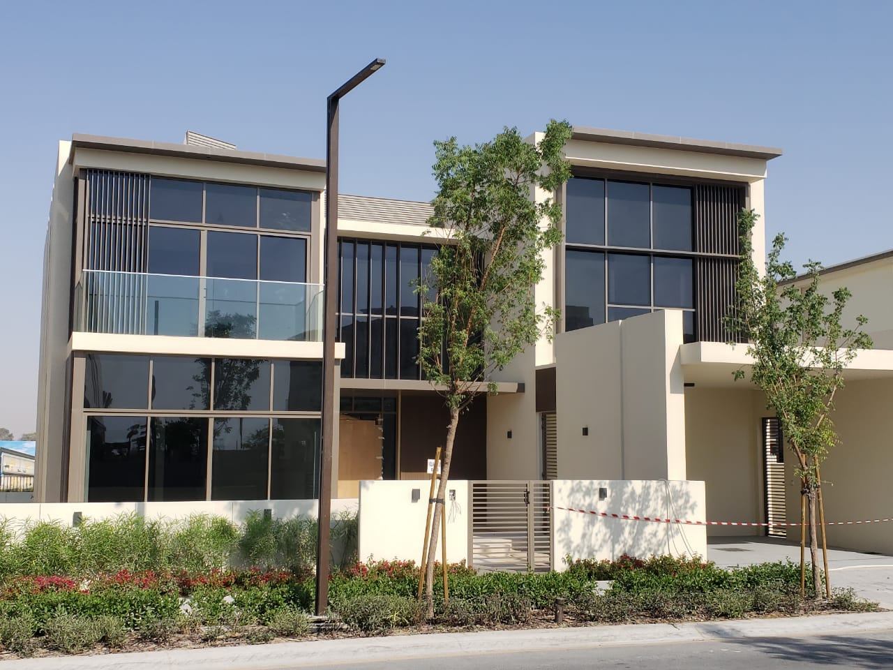 A modern villa with dark ACP frames, large windows and glass balconies